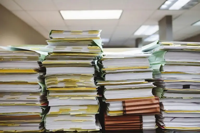 Stack of papers in folders piled up on a desk